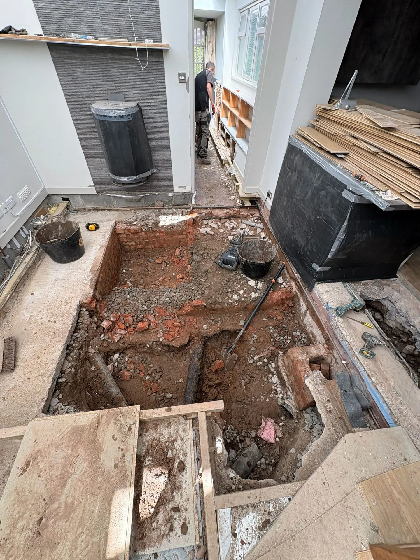 Indoor excavation revealing brick chamber and old pipework